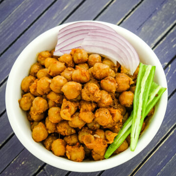 Pindi chana garnished with sliced onions and slit green chili.