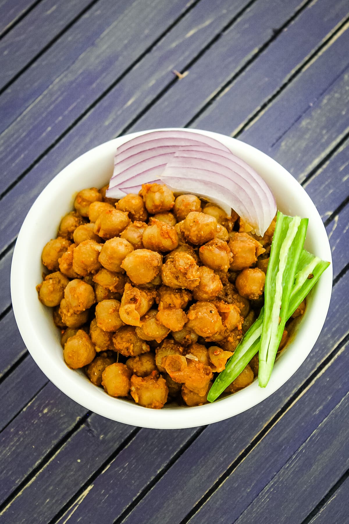 Pindi chana garnished with sliced onions and slit green chili.