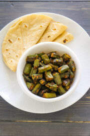 Achari bhindi served with a bowl with 3 phulka roti.