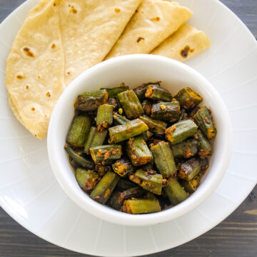 Achari bhindi served with a bowl with 3 phulka roti.