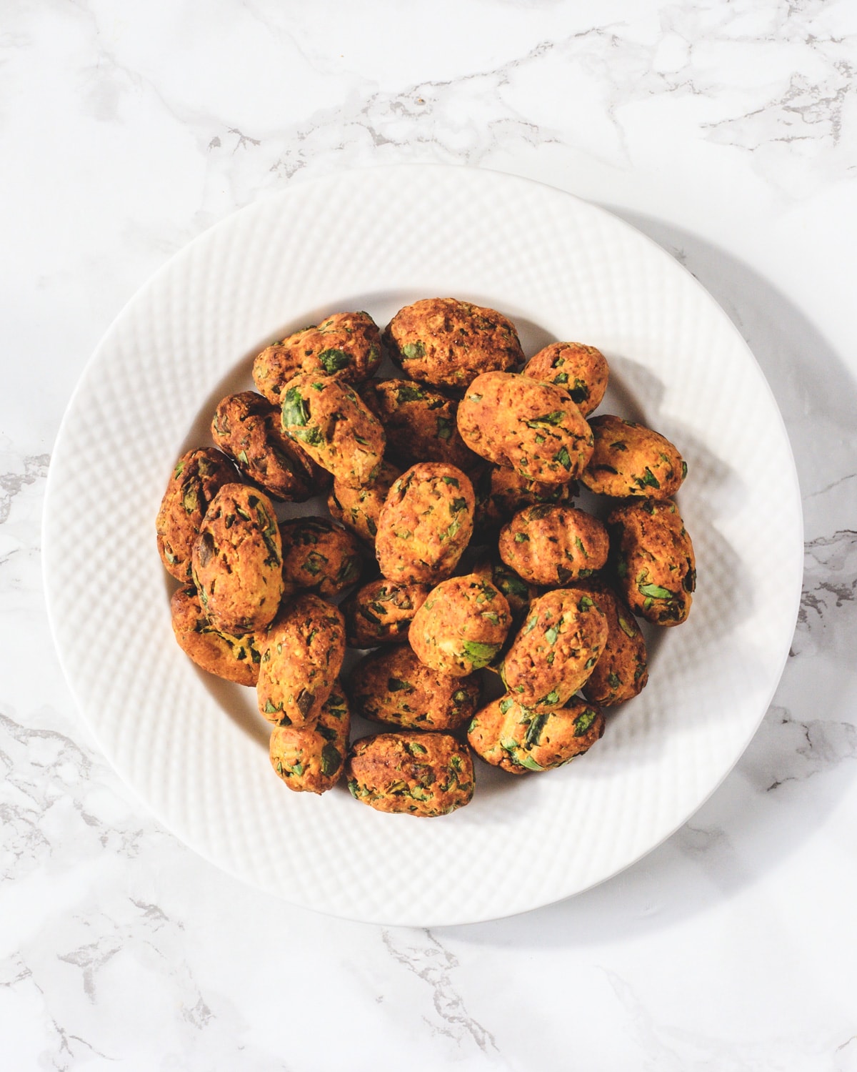 Air fryer methi muthi in a round white plate.