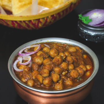 Close up of chole masala garnished with onion rings.