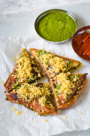 Masala toast sandwich garnished with sev and served with green chutney, ketchup.