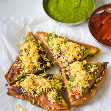 Masala toast sandwich garnished with sev and served with green chutney, ketchup.