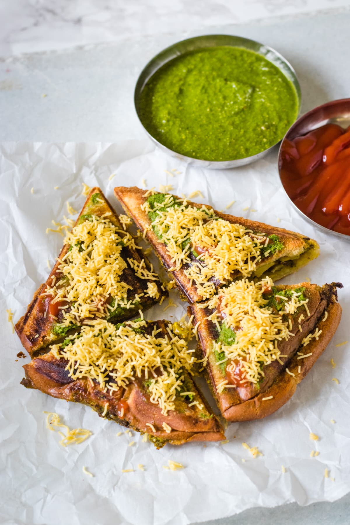 Masala toast sandwich garnished with sev and served with green chutney, ketchup.