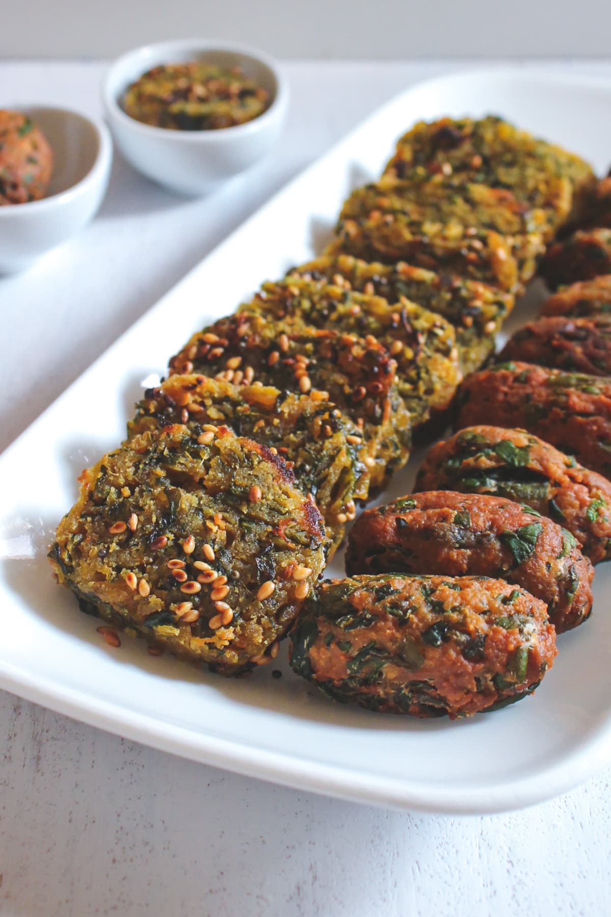 Close up of steamed and fried methi muthia lined up in a rectangle plate.
