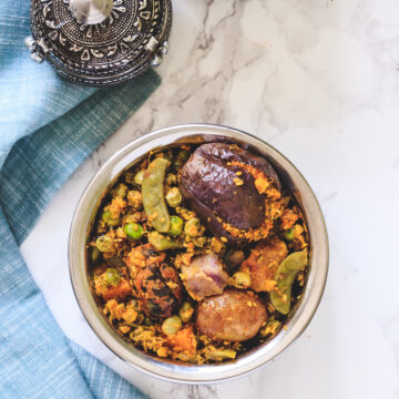 Top view of undhiyu in steel bowl with napkin on side.