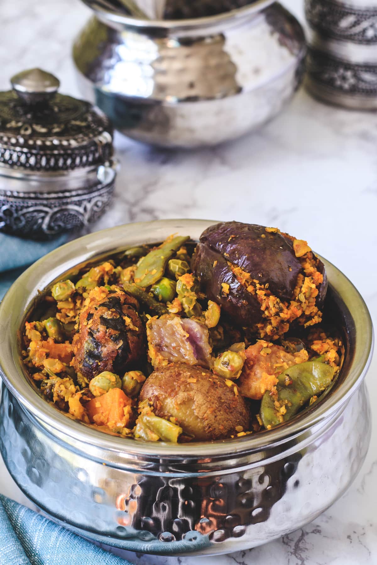 Undhiyu served in a steel handi with few steel containers in the background.