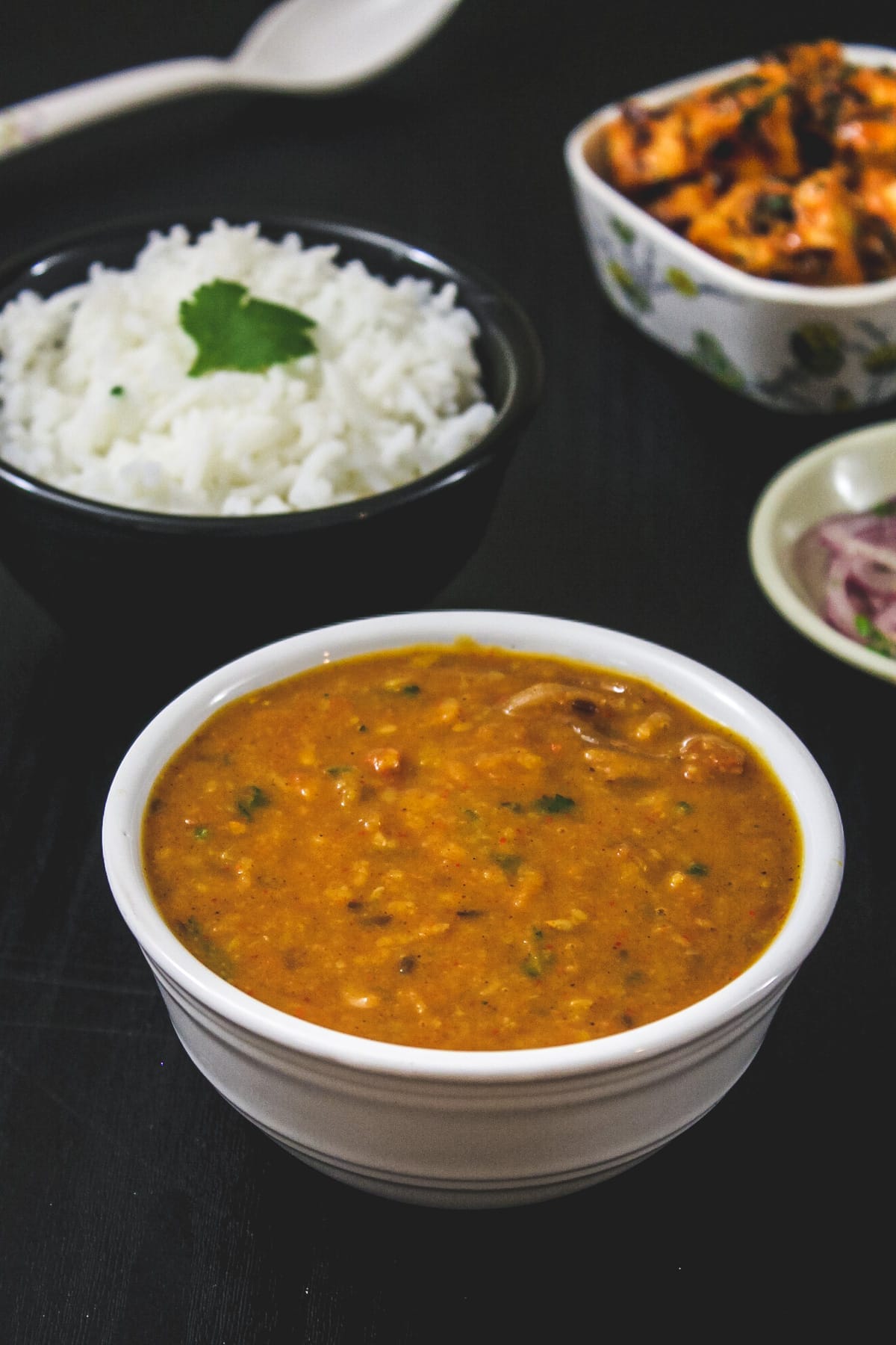 Toor dal in a bowl with side of rice and paneer sabzi.