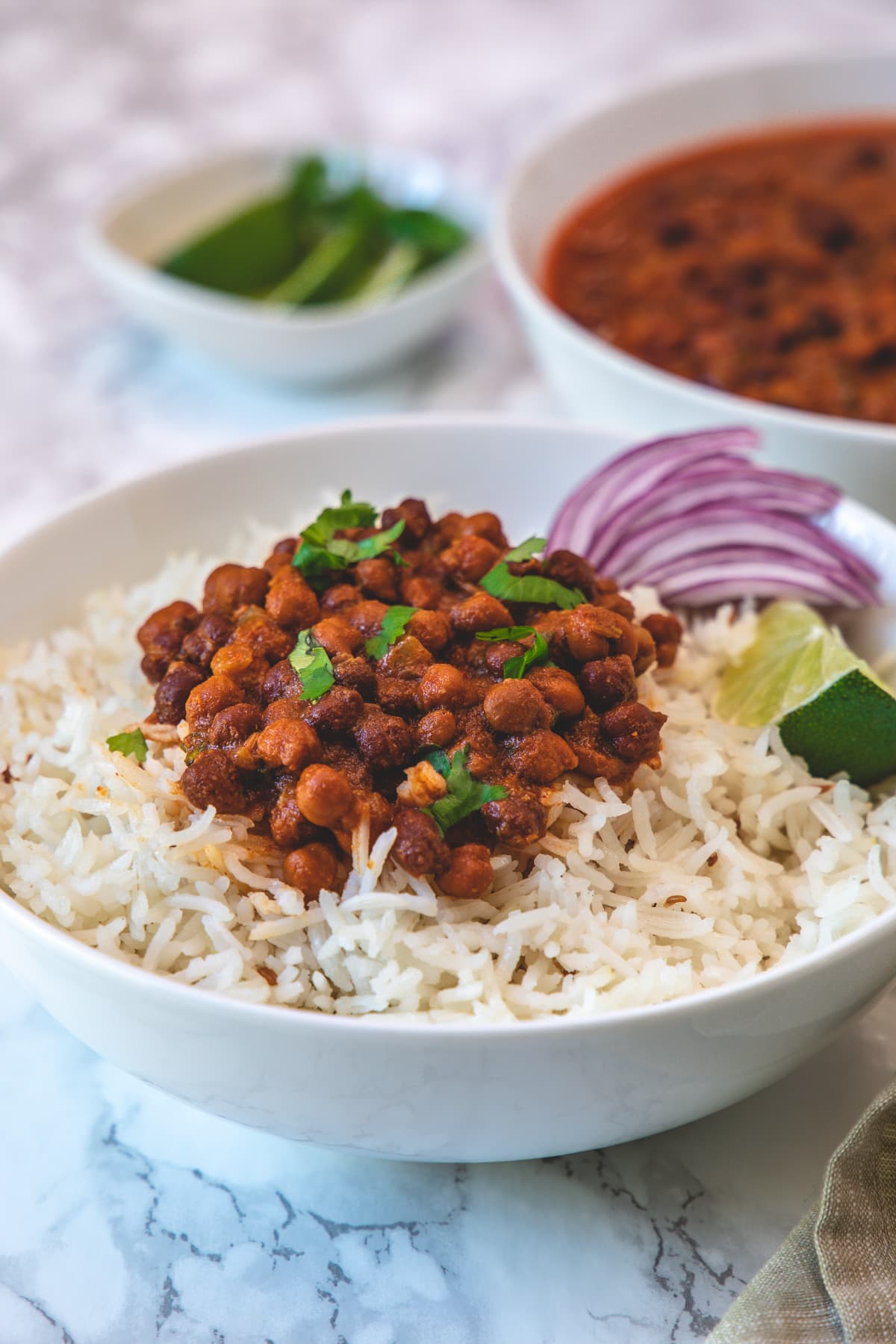 Kala chana masala served over a bowl of rice with side of sliced onions and lime wedge.