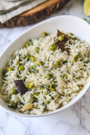 Close up of peas pulao in an oval white bowl.