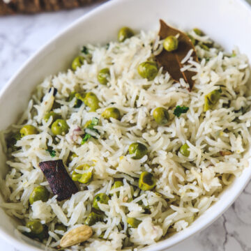 Close up of peas pulao in an oval white bowl.
