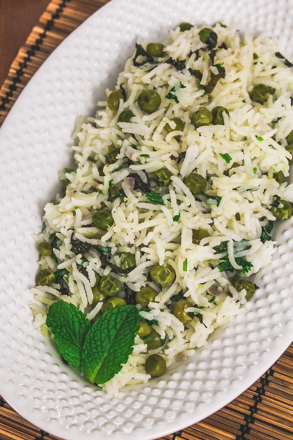 Peas pulao in a plate garnished with mint leaves.