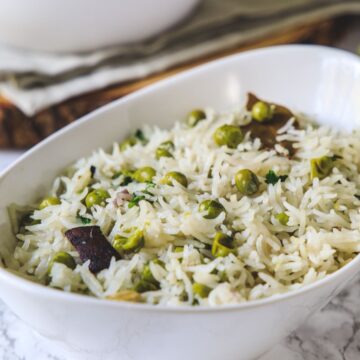 Peas pulao in a white oval bowl.