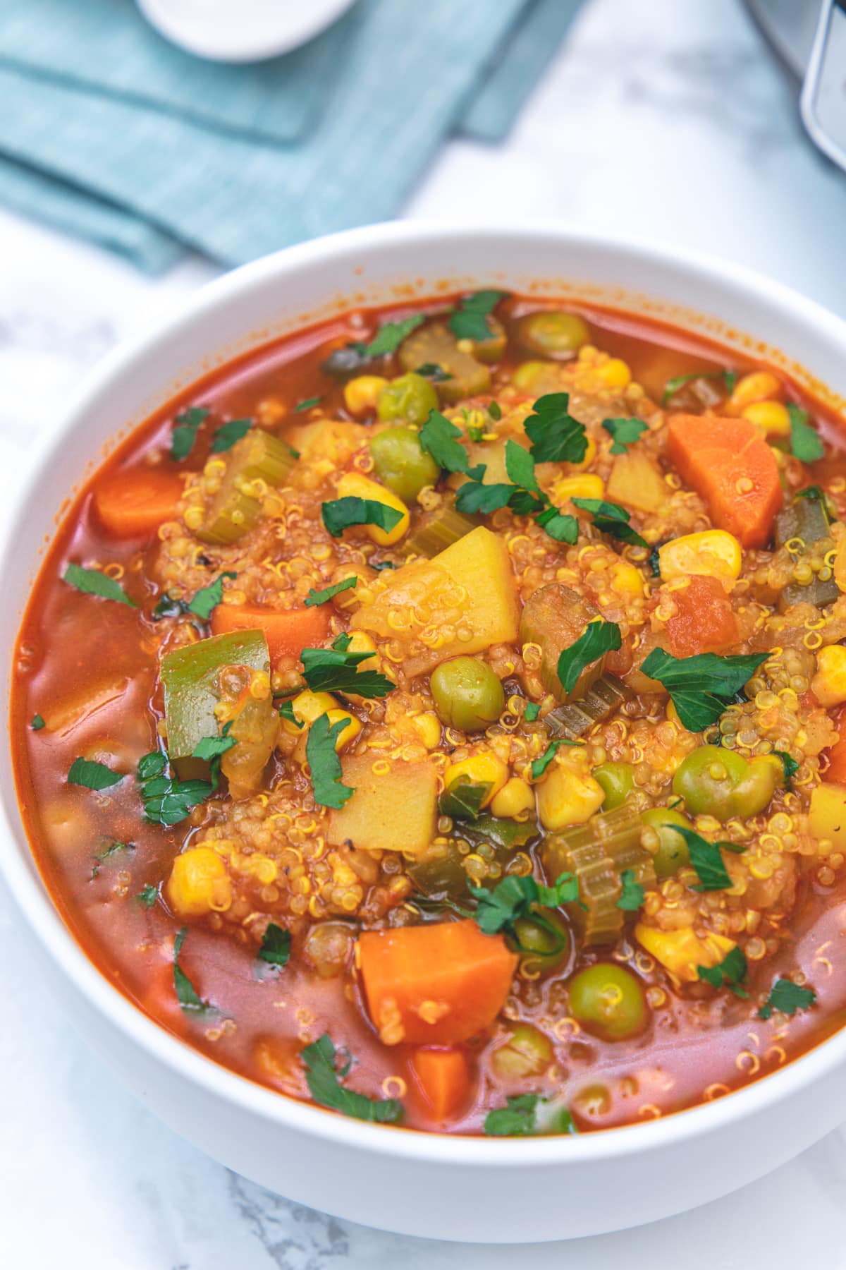 Close up of instant pot quinoa vegetable soup served in a bowl, garnished with parsley.