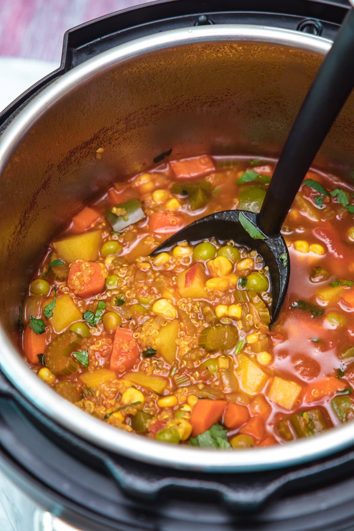 quinoa vegetable soup in instant pot ready to take a ladleful for serving.