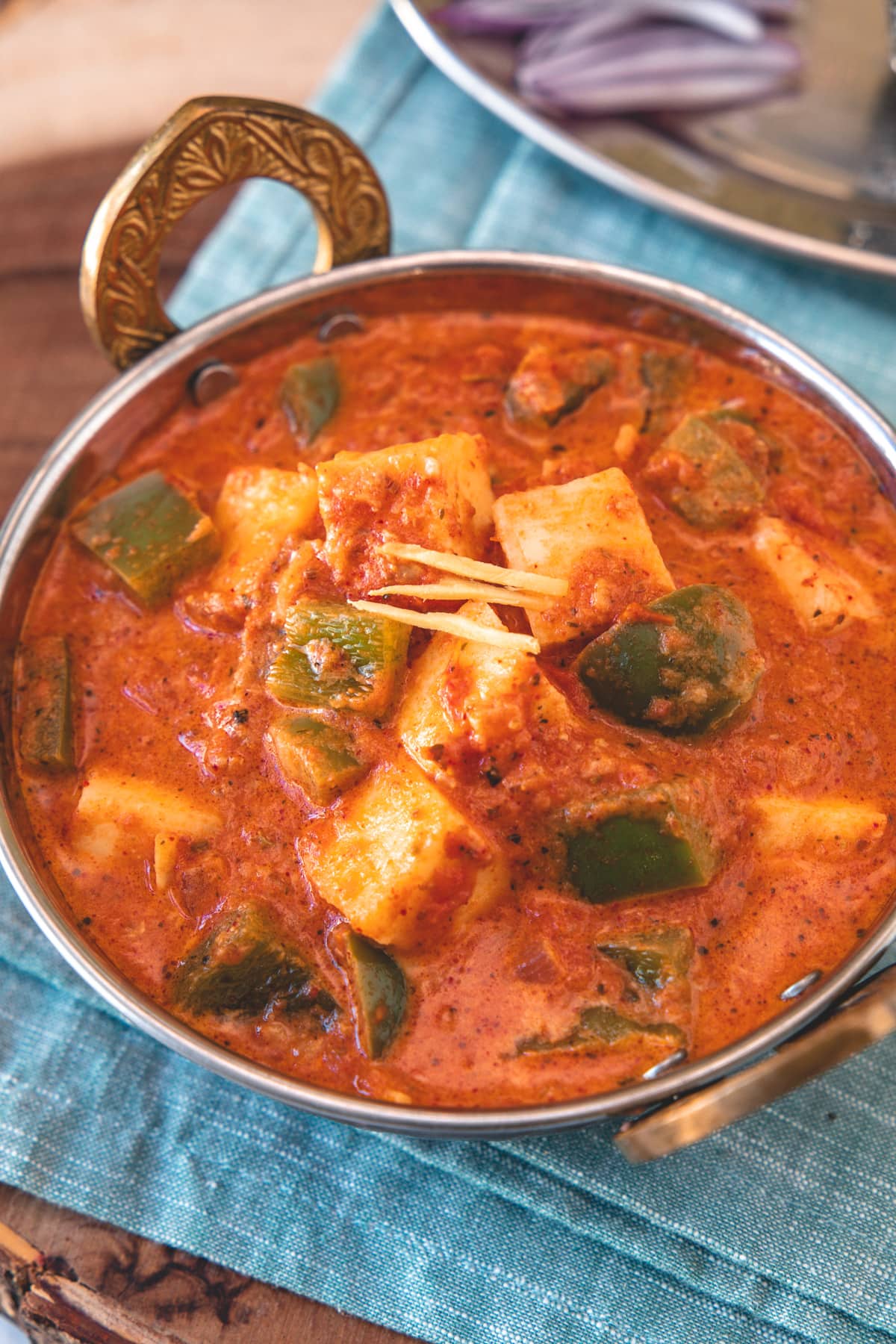 Close up of kadai paneer in a serving wok with napkin underneath.