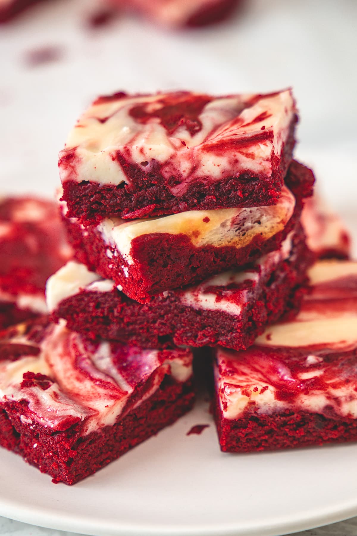 Stack of red velvet cheesecake brownies in a white plate.