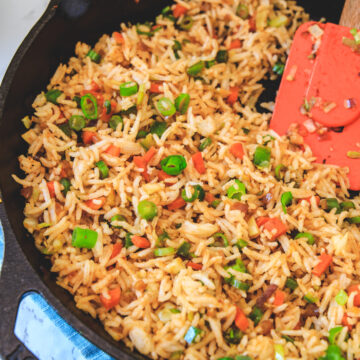 schezwan fried rice in a cast iron pan with spatula.