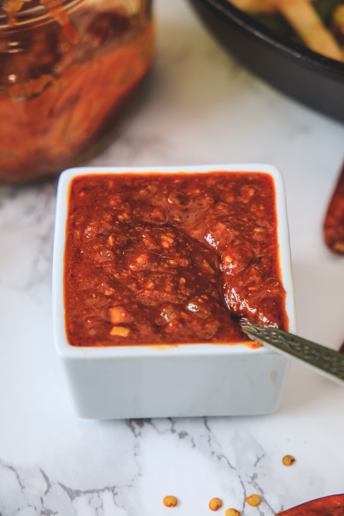 schezwan sauce in a white bowl with spoon.