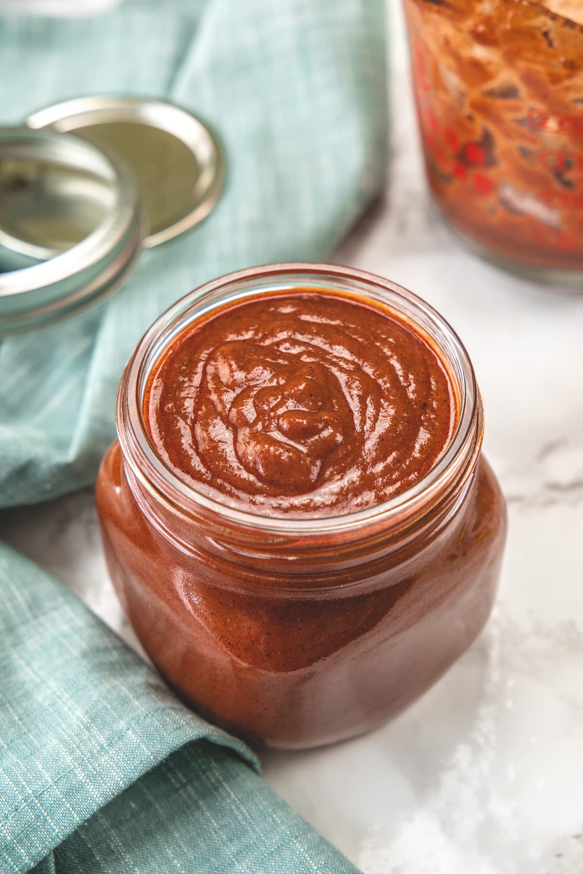 Enchilada sauce in a glass jar with napkin on side.