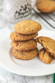 Stack of 4 eggless coconut cookies in a plate with one cookie broken into half on the side.