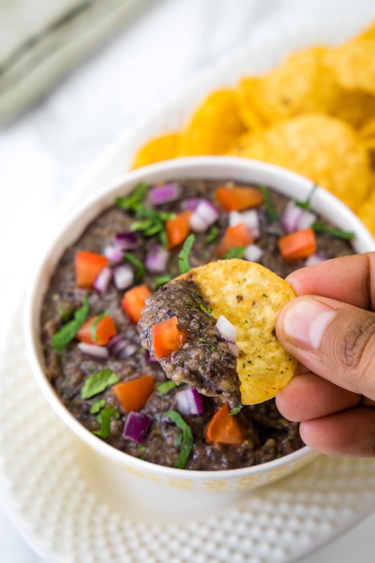 A scoop of black bean dip with tortilla chip.