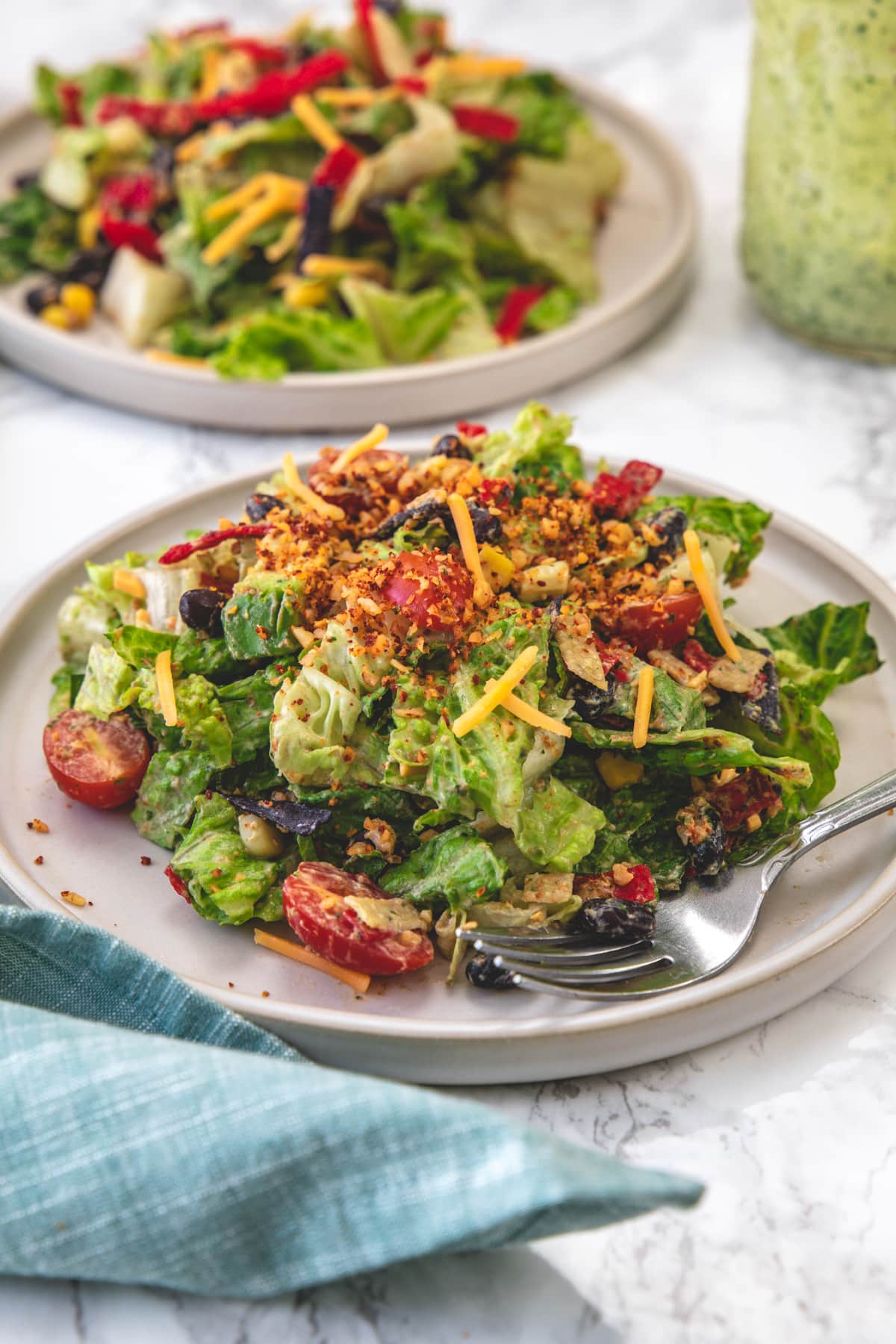 Close up of vegetarian taco salad served in a plate with fork and napkin on side.