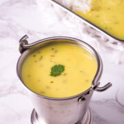 Gujarati kadhi in a balti serving dish with a garnish of cilantro leaf.