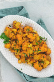 Aloo gobi masala served in an oval platter and garnished with cilantro.