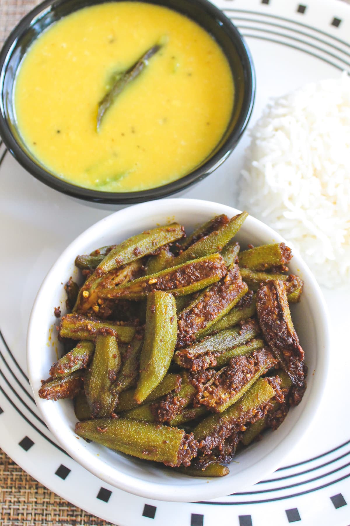 Bhindi masala served in a bowl with dal and rice.
