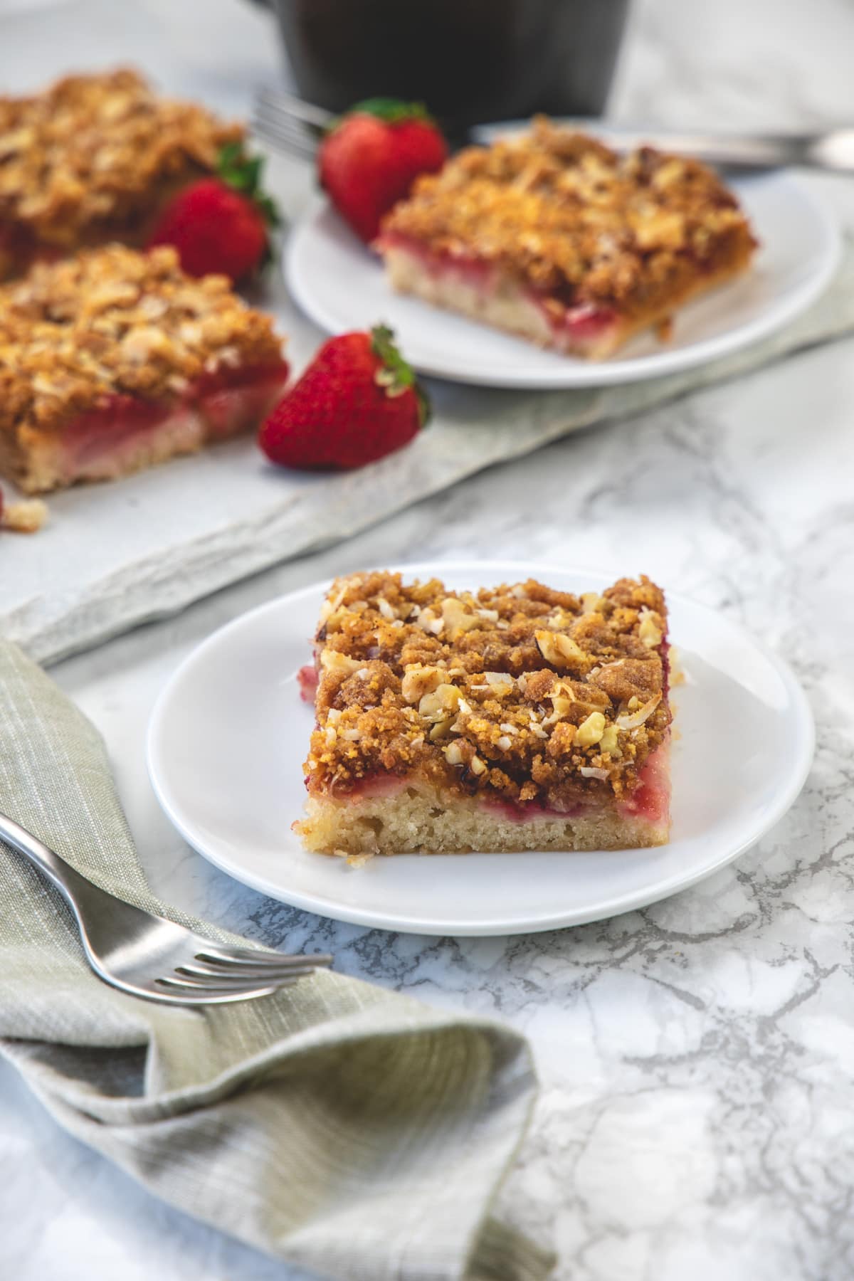 Eggless strawberry cake piece served on a plate with fork & napkin on side.