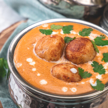 Malai kofta garnished with cilantro leaves.