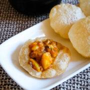 Aloo curry served on puri with few more puri and curry on side.