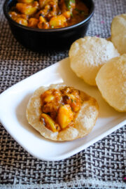 Aloo curry served on puri with few more puri and curry on side.