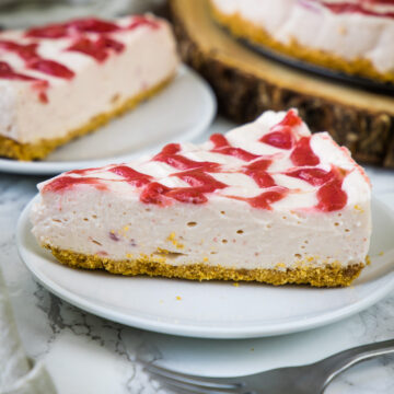 A close up of no bake strawberry cheesecake slice served on a plate with fork on side.