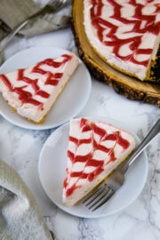 2 sliced of strawberry cheesecake served in plate and remaining on back side.