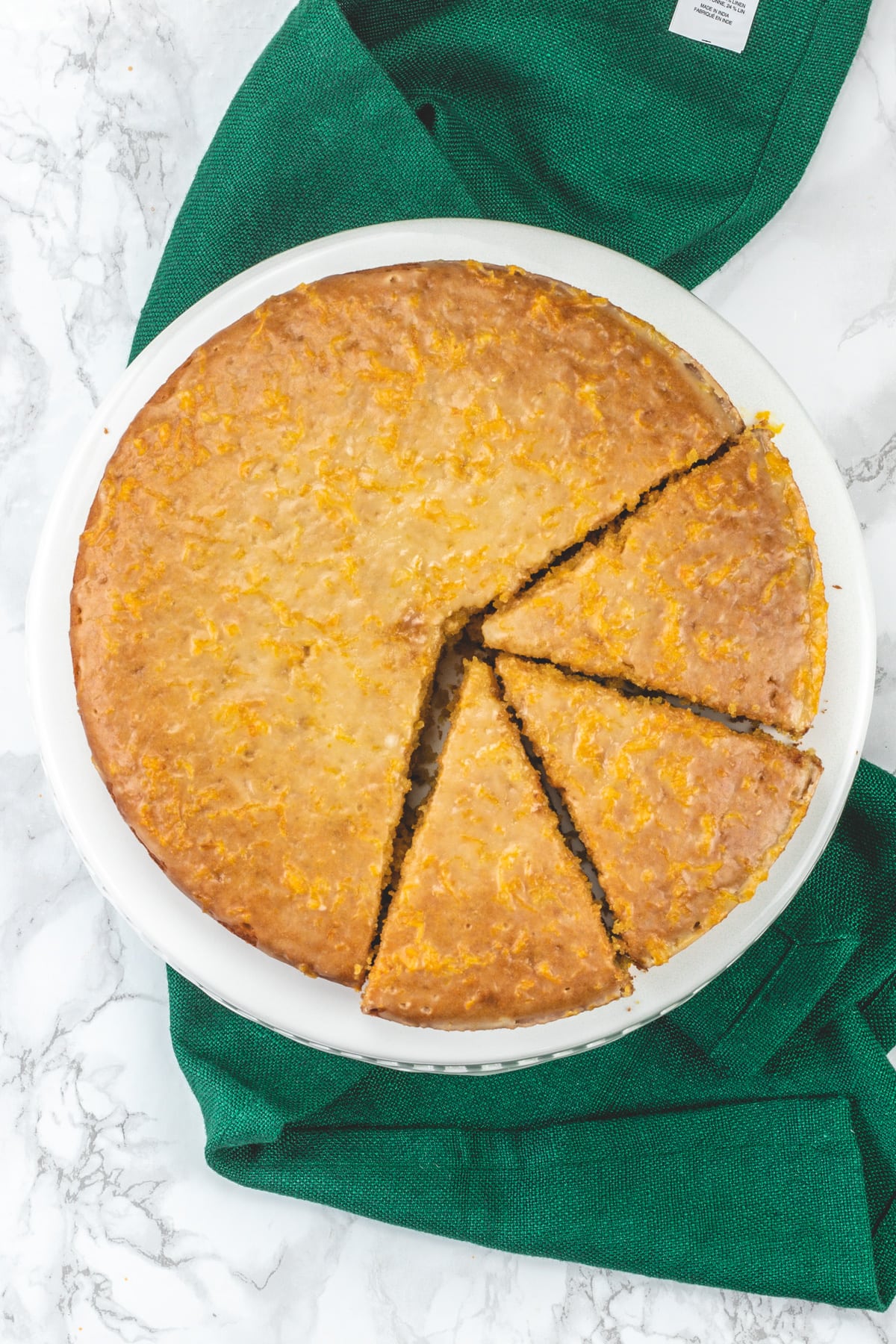 Top view of eggless orange cake on the cake stand with green napkin.