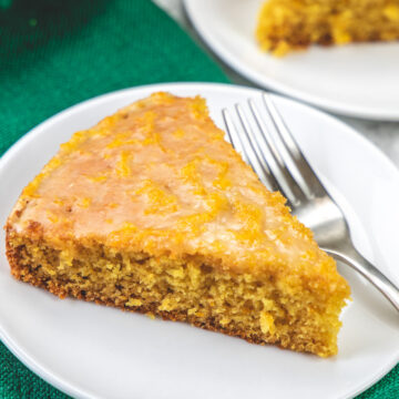 A slice of orange cake in a plate with fork.