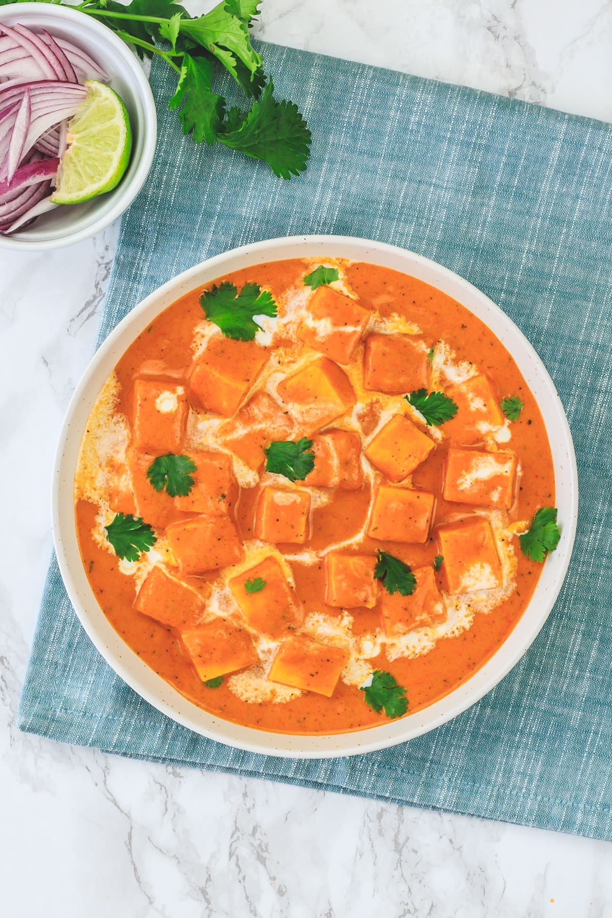 Top view of paneer makhani served in a wide bowl with napkin underneath.