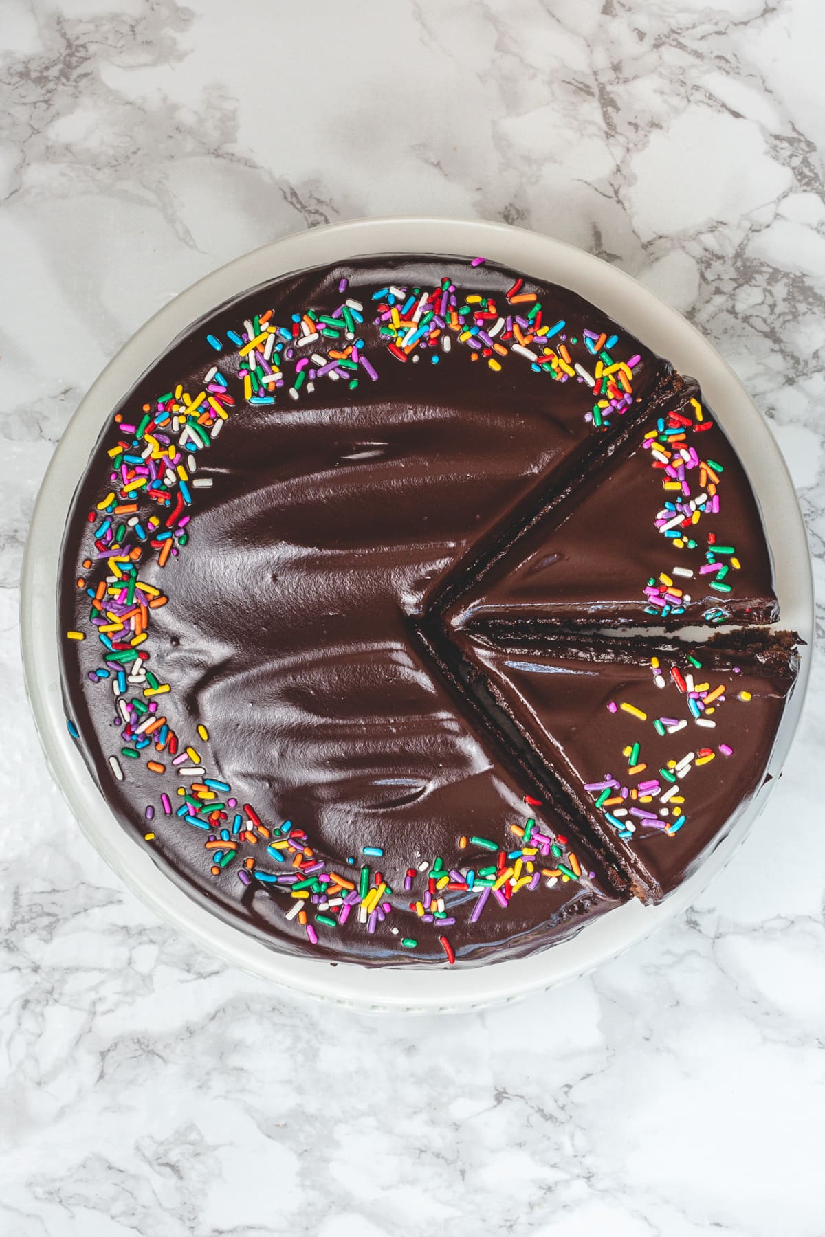 Top view of eggless chocolate cake with two slices on a cake stand.