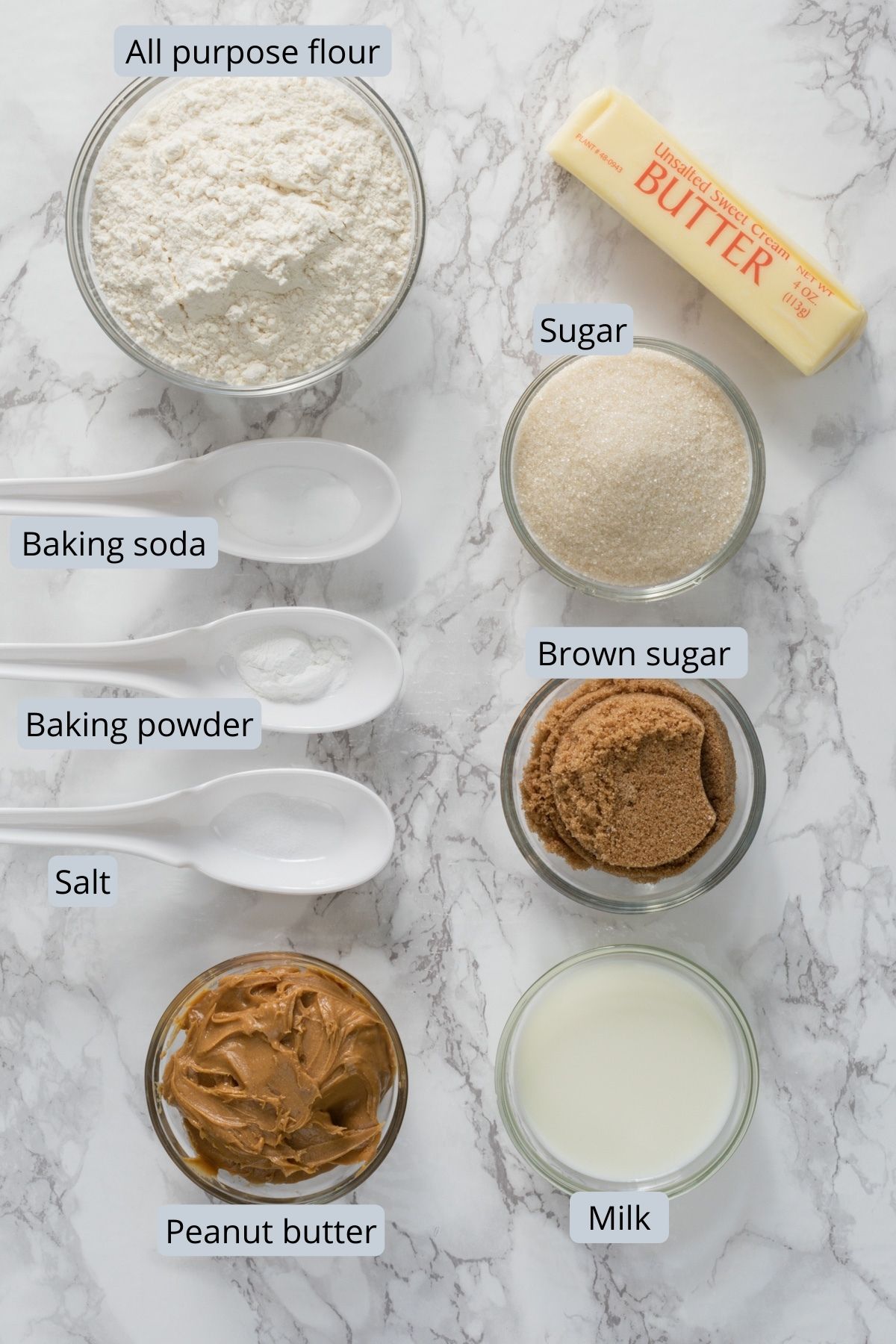 Ingredients used for eggless peanut butter cookies in individual bowls and spoons.