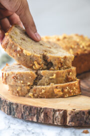 A stack of banana bread slices on a wooden board and taking away one slice.