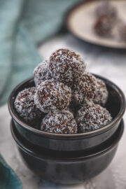 Stack on coconut date balls in a stack of 2 black bowls.
