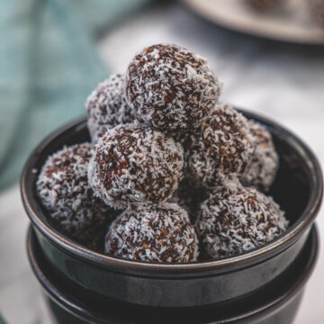 Stack on coconut date balls in a stack of 2 black bowls.