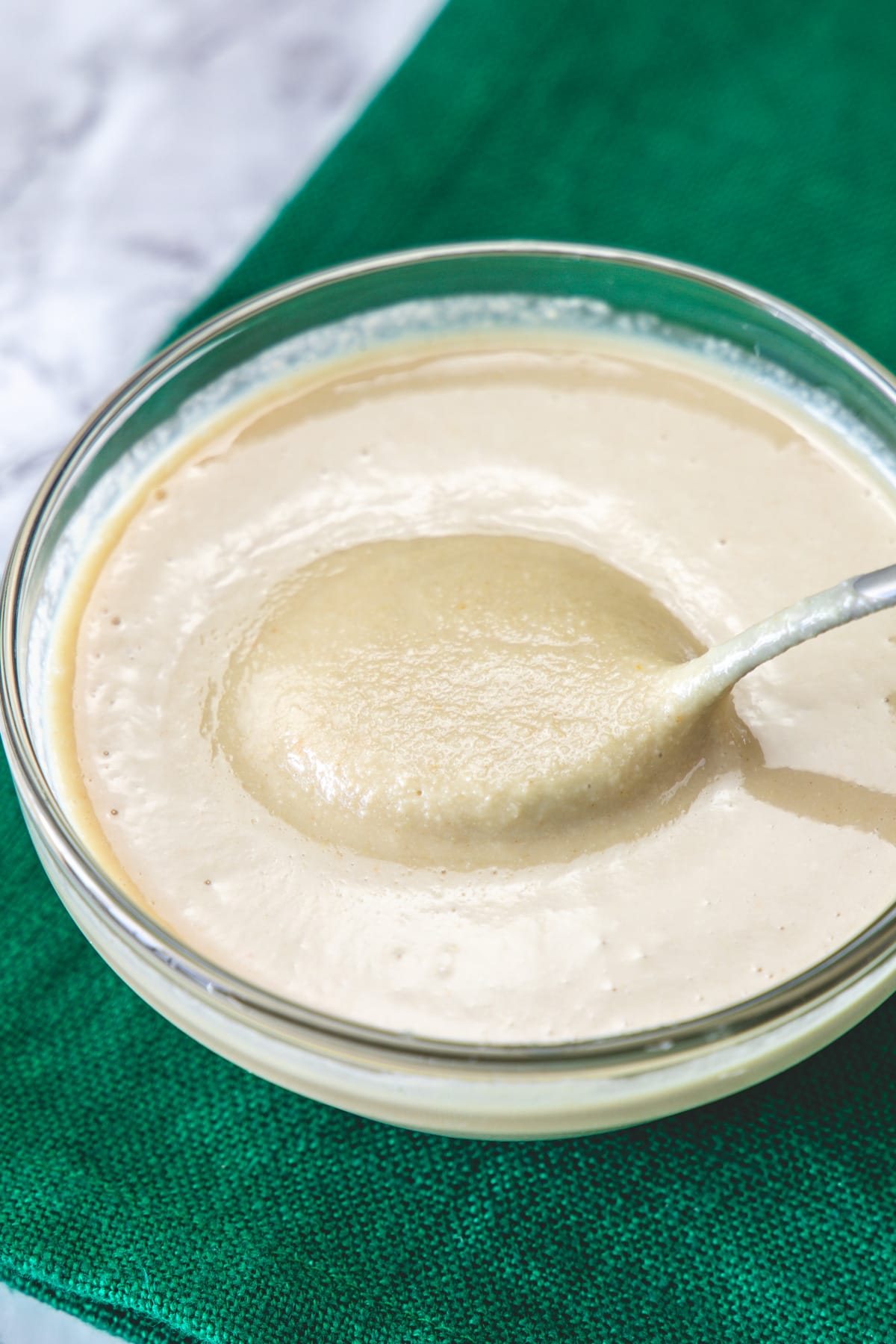 Homemade tahini in a bowl taking away with a spoon.