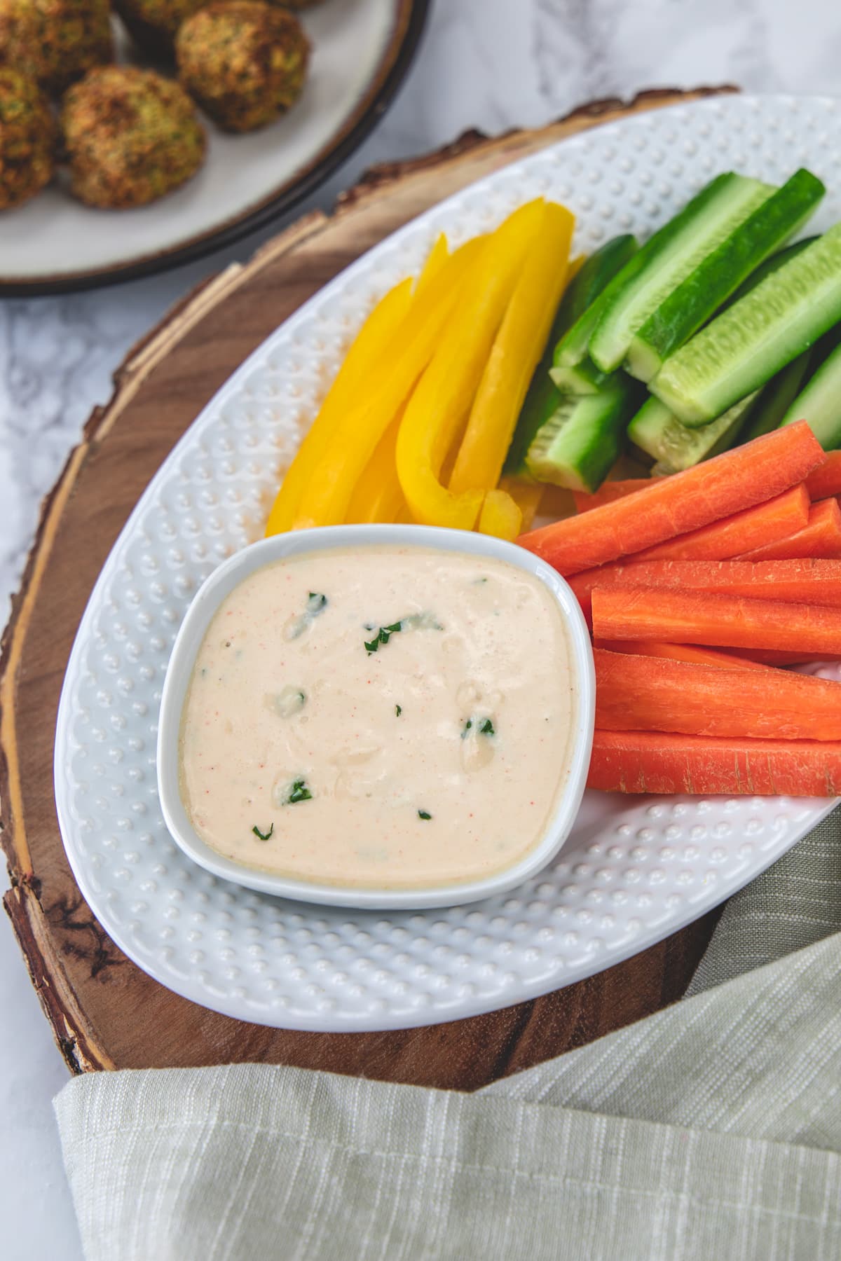 Tahini sauce served with carrot, cucumber, yellow peppers and falafel.