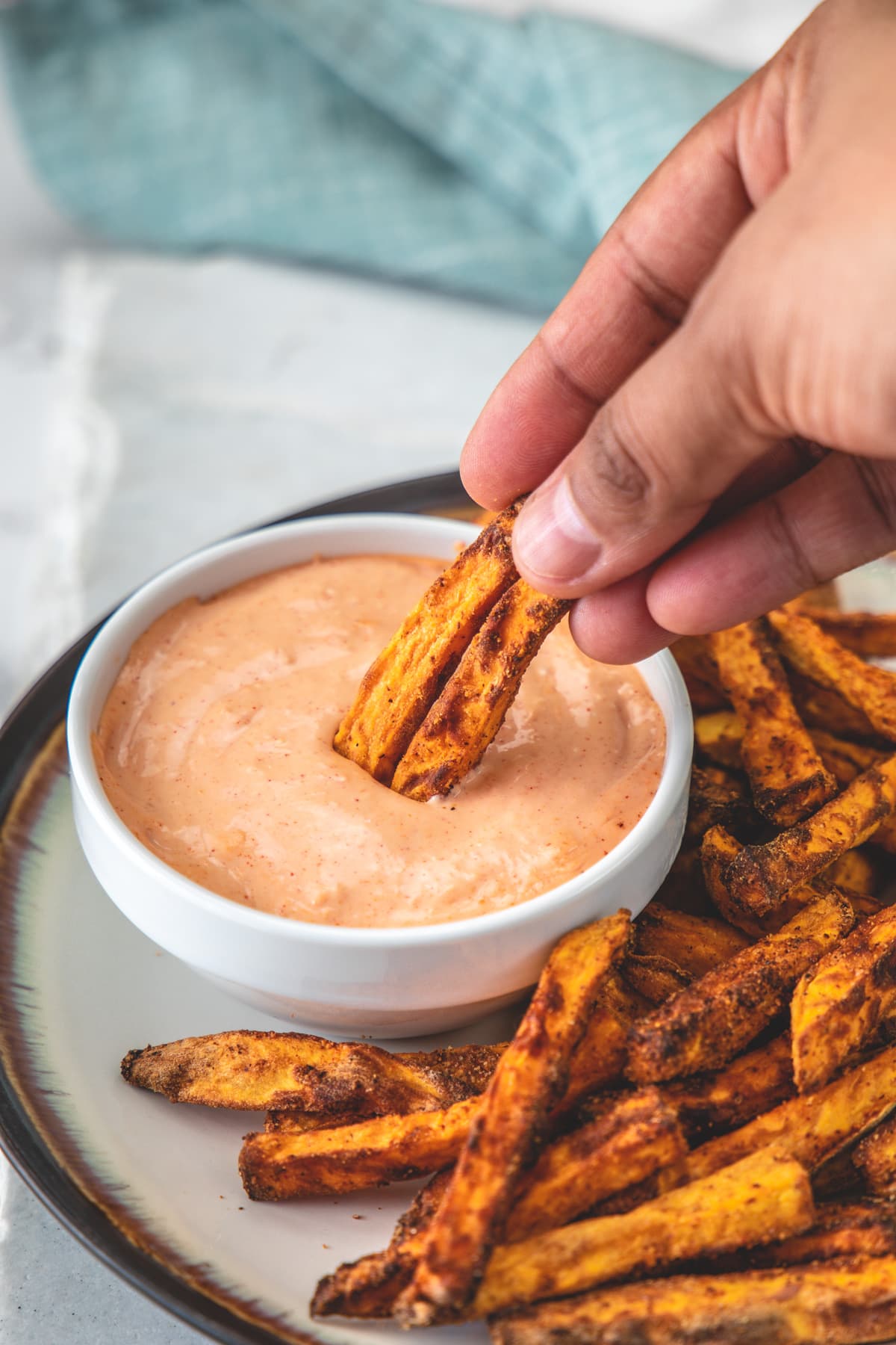2 air-fried sweet potato fries dipping into the fry sauce.