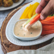 Dipping carrot and cucumber in tahini sauce.