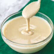 Drizzling tahini with a spoon back into the bowl to show texture.